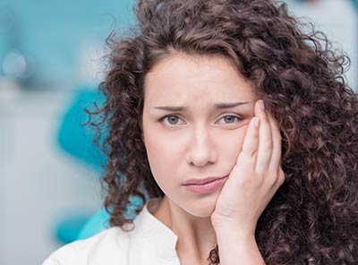 woman holding her mouth from tooth pain